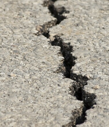 Close-up of a pavement crack indicating infrastructure damage. AP Sensing fiber optic sensing detects such critical issues Close-up of a pavement crack indicating infrastructure damage. AP Sensing fiber optic sensing detects such critical issues