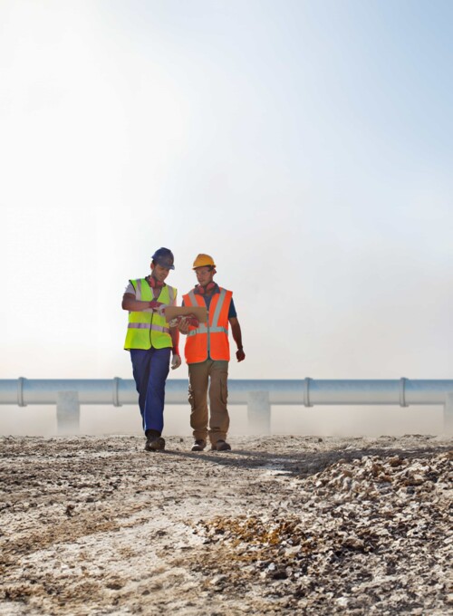 Engineering team in front of a pipeline Experten inspizieren Pipeline-Baustelle für effiziente Überwachung und Sicherheit der Infrastruktur