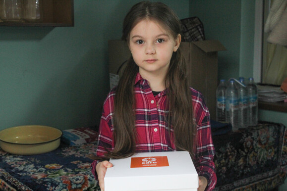 Young girl holding a white box with an orange logo sticker Young girl holding a white box with an orange logo sticker