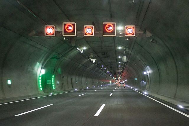 Tunnel highway with overhead signs, illustrating critical infrastructure monitored by AP Sensing fiber optic sensing for safety Tunnel highway with overhead signs, illustrating critical infrastructure monitored by AP Sensing fiber optic sensing for safety